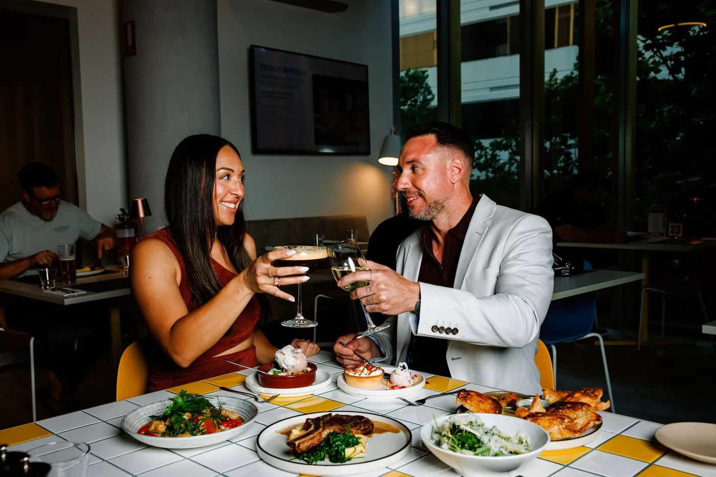 Two guests toasting with an espresso martini and a glass of white wine over dinner at Eastside Social